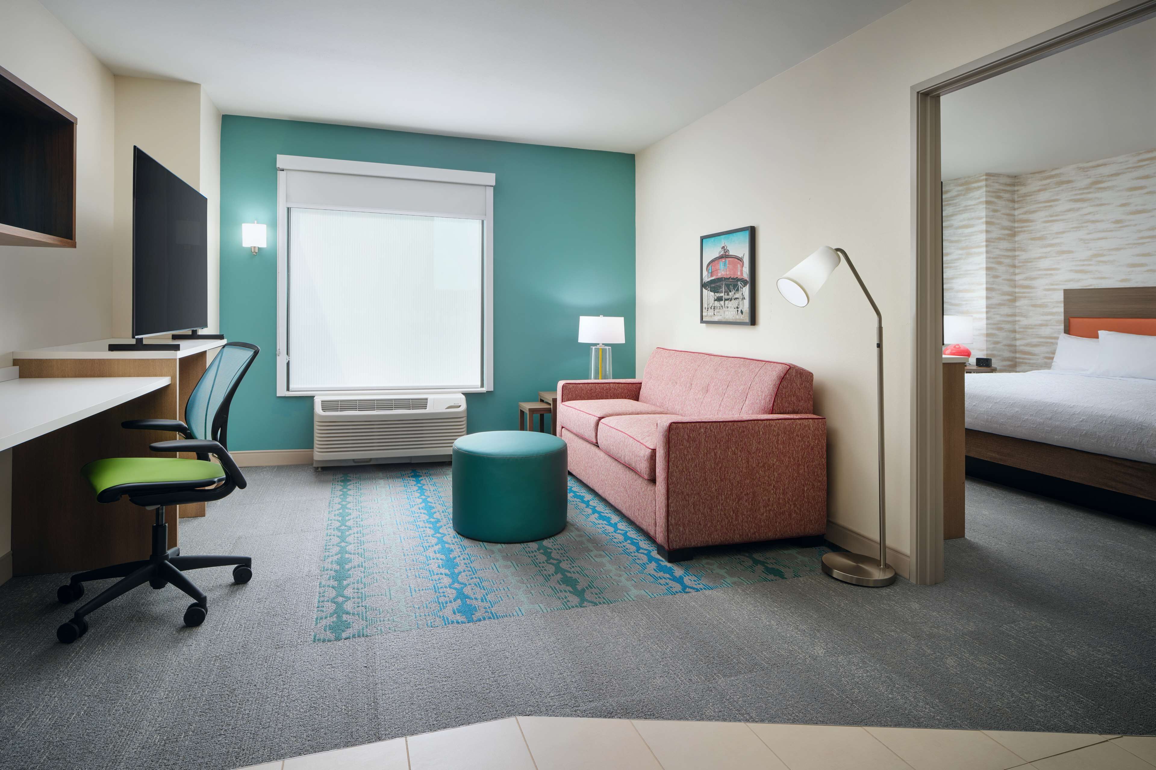 Una habitación de hotel con escritorio, silla, sofá y cama.
