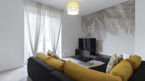 A modern living room with a sofa, a desk, and a television.