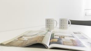 Deux tasses blanches ornées du logo Italianway sont posées sur une table, à côté d’un magazine ouvert.
