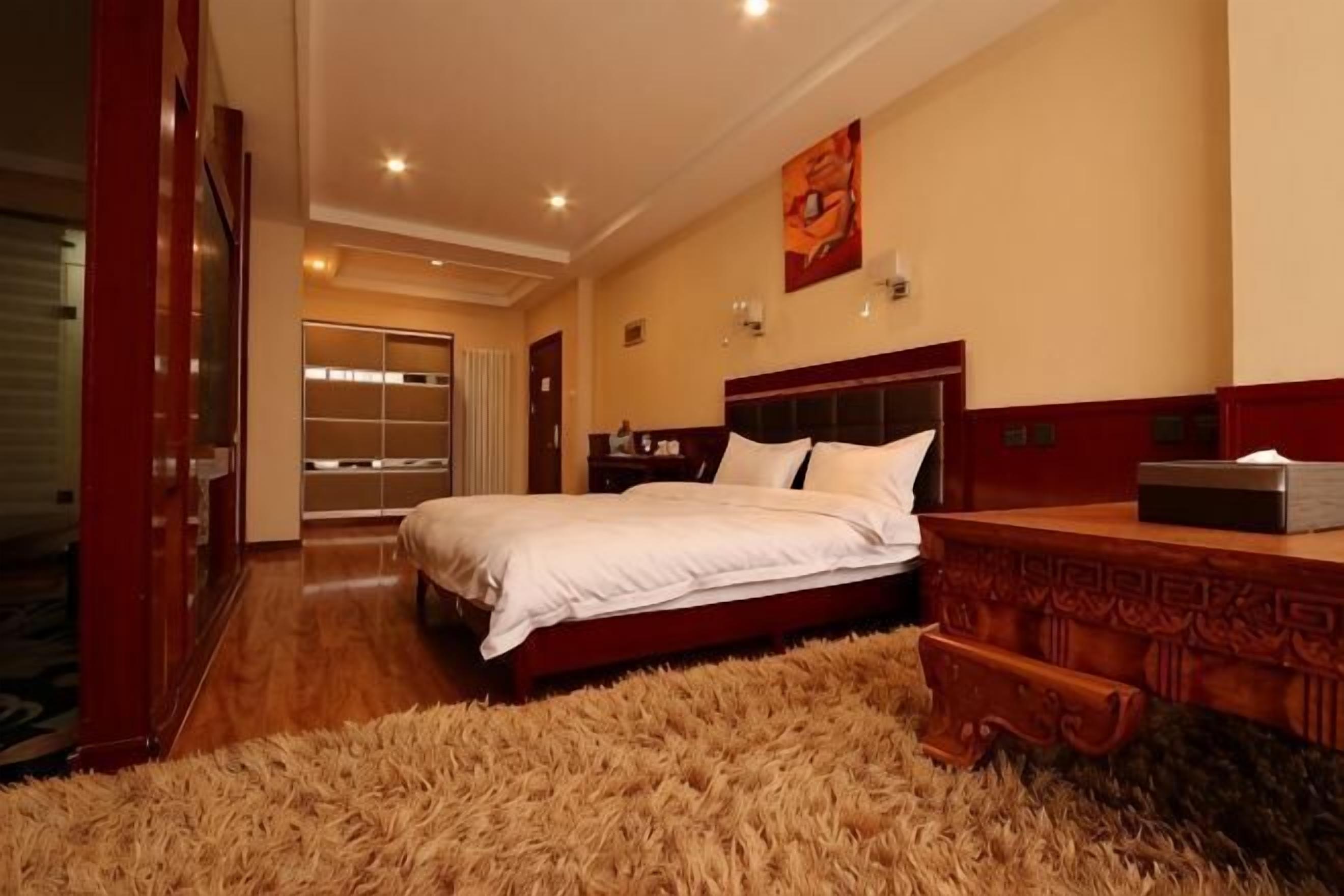 Une chambre à coucher avec un lit, une table de chevet en bois, un miroir et une grande fenêtre.