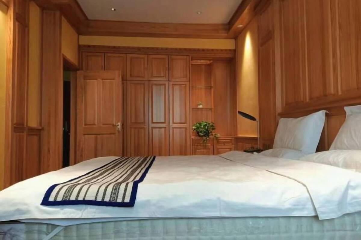 Un dormitorio con una cama grande, un armario de madera y una planta pequeña en la mesita de noche.