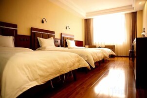 A hotel room with two beds, a desk, and a large window.