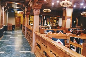 Un restaurant avec des bancs et des tables en bois, un sol en marbre et des luminaires suspendus.