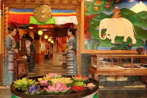 Un interior con un corredor central, una pared decorativa con un cuadro de un elefante y una vitrina con objetos.