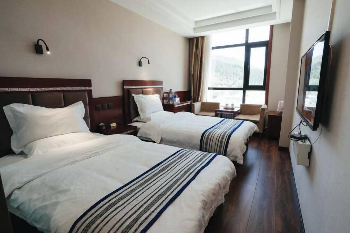 Habitación de hotel con dos camas, un ventanal con vistas, un televisor de pantalla plana y una mesita.