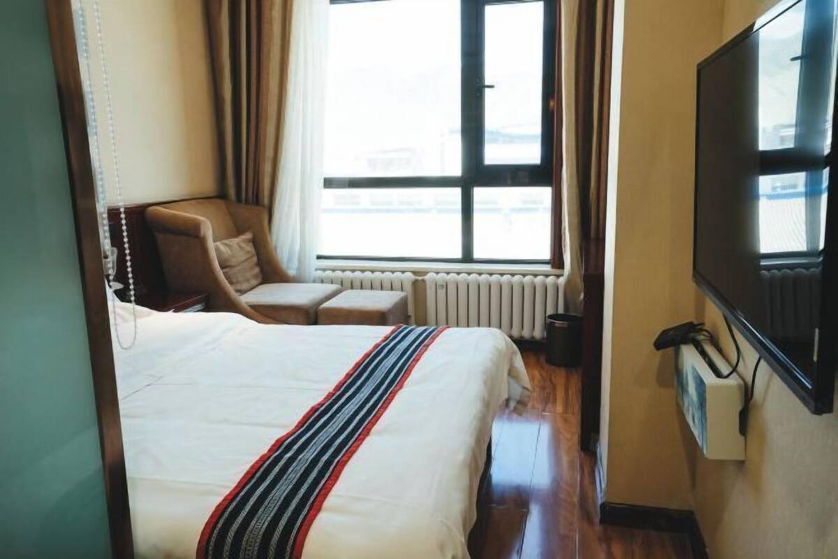 Una habitación de hotel con una cama, una silla, un televisor y una ventana.