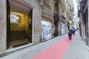 A narrow street with a red carpet, shops on either side, and a staircase leading to an entrance. - San Luca Apartments - Pallavicini by Wonderful Italy (Genoa)