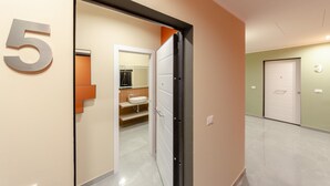 A hallway with a number '5' sign, a bathroom with a sink and mirror, and a door with a '3' sign. - San Luca Apartments - Pallavicini by Wonderful Italy (Genoa)