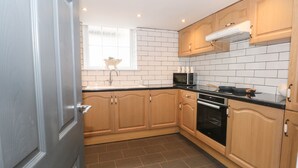Een moderne keuken met houten kastjes, een zwart aanrecht, een ingebouwde magnetron en een roestvrijstalen oven.