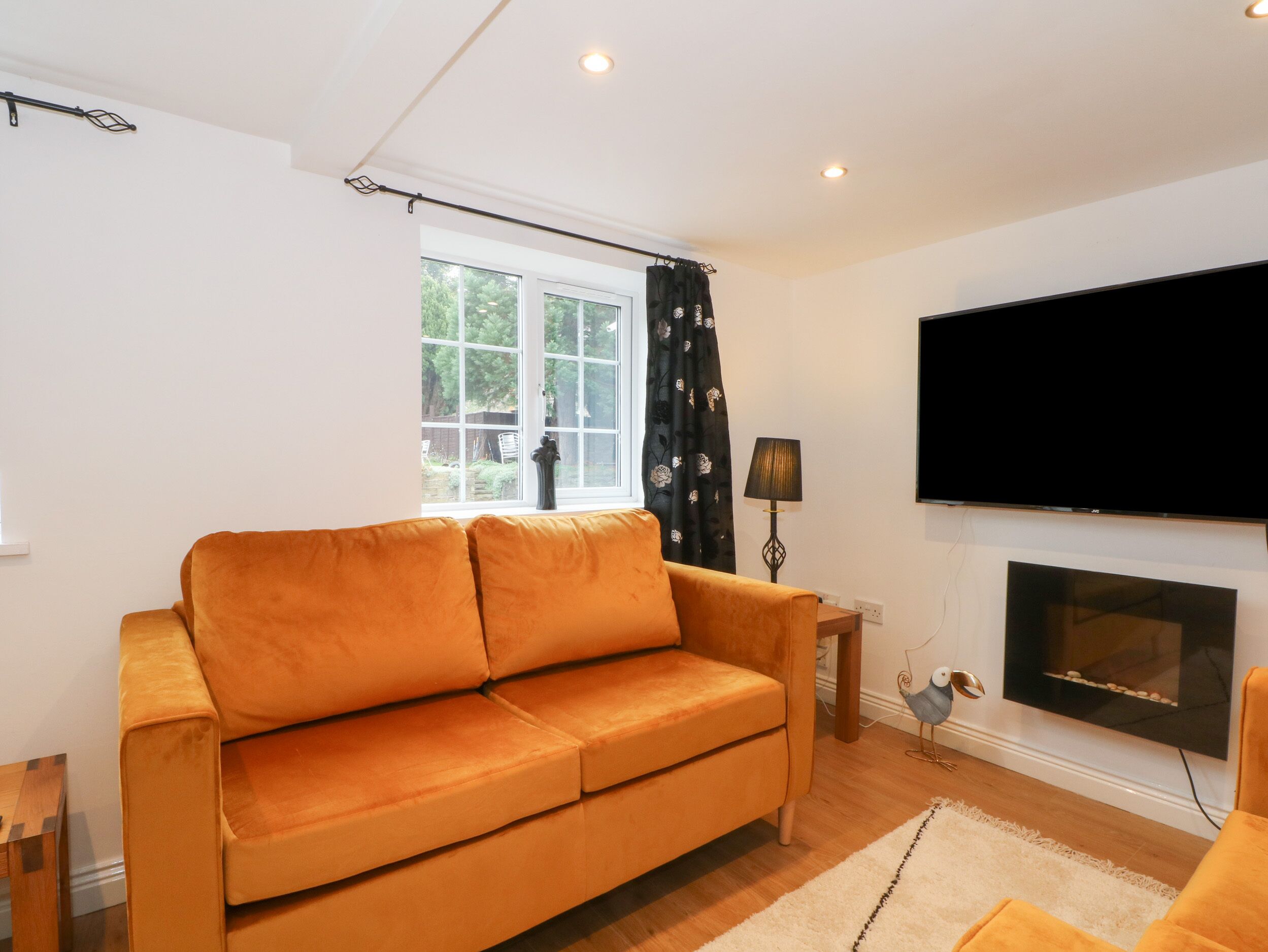Una sala de estar con un sofá, un televisor, una chimenea y una ventana con cortinas.