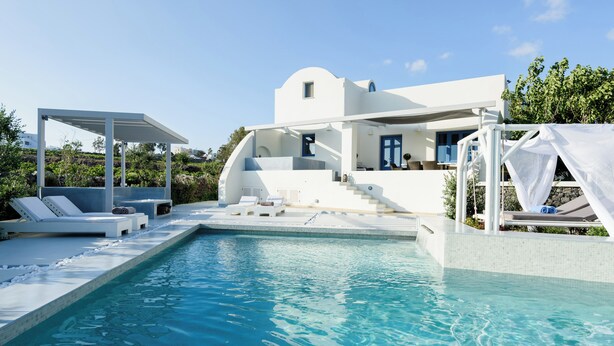Una villa moderna y blanca con piscina, mobiliario exterior y un porche cubierto.