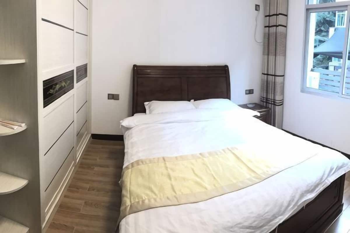 Una camera da letto con un letto, un comodino, una finestra con tende e scaffalature a incasso.