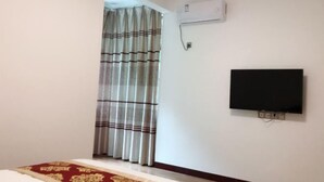 A room with a bed, a television mounted on the wall, and an air conditioning unit. - Qingyunshan Jieyou Hostel (Yongtai)