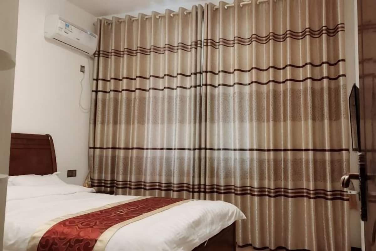Una camera d'albergo con un letto, tende e un condizionatore.