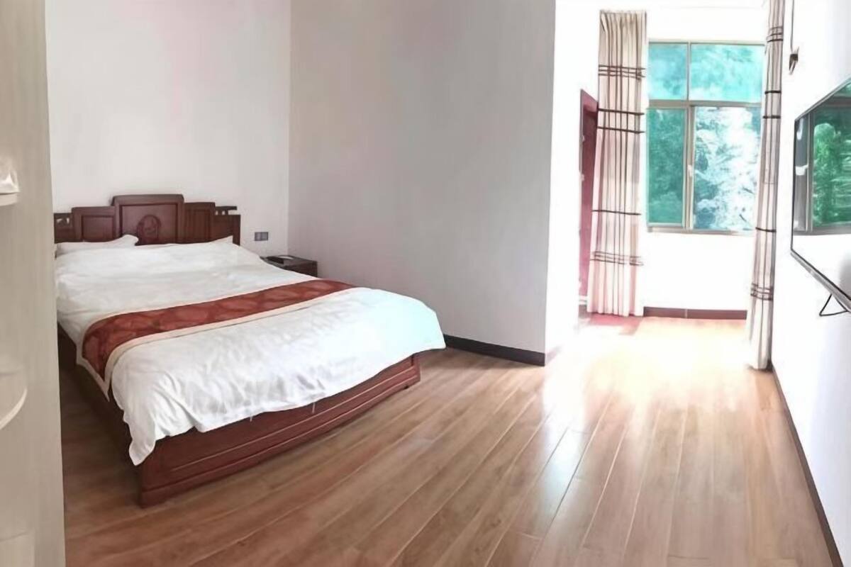 Una camera da letto con un letto in legno, un comodino, una finestra con tende e un televisore a parete.