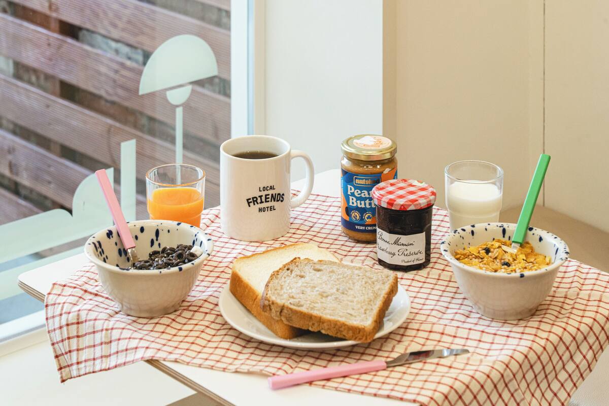 A breakfast setup with toast, cereal, milk, juice, and coffee on a checkered tablecloth.