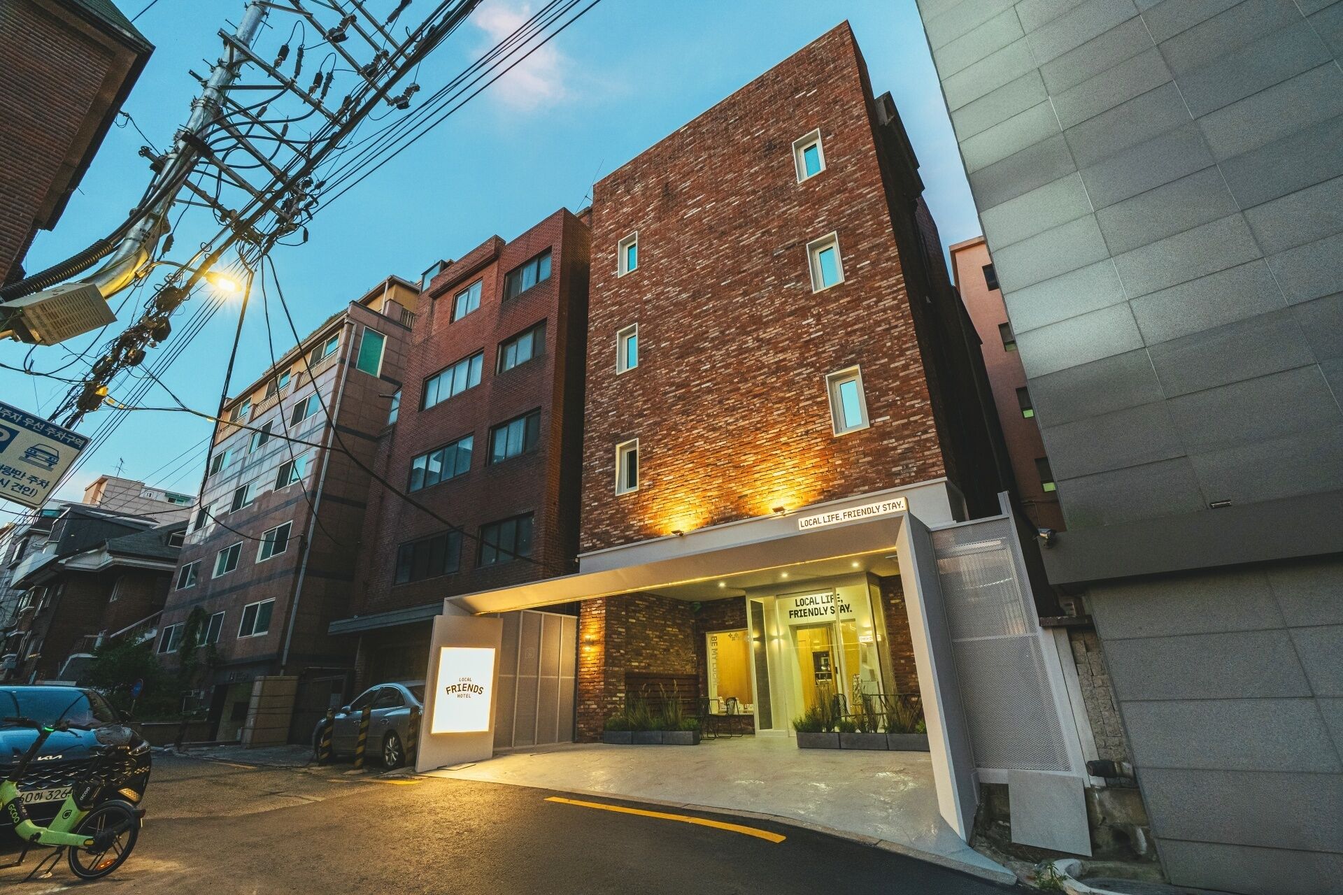 A hotel with a brick facade, multiple windows, and a sign indicating 'LOCAL LIFE. FRIENDLY STAY.'