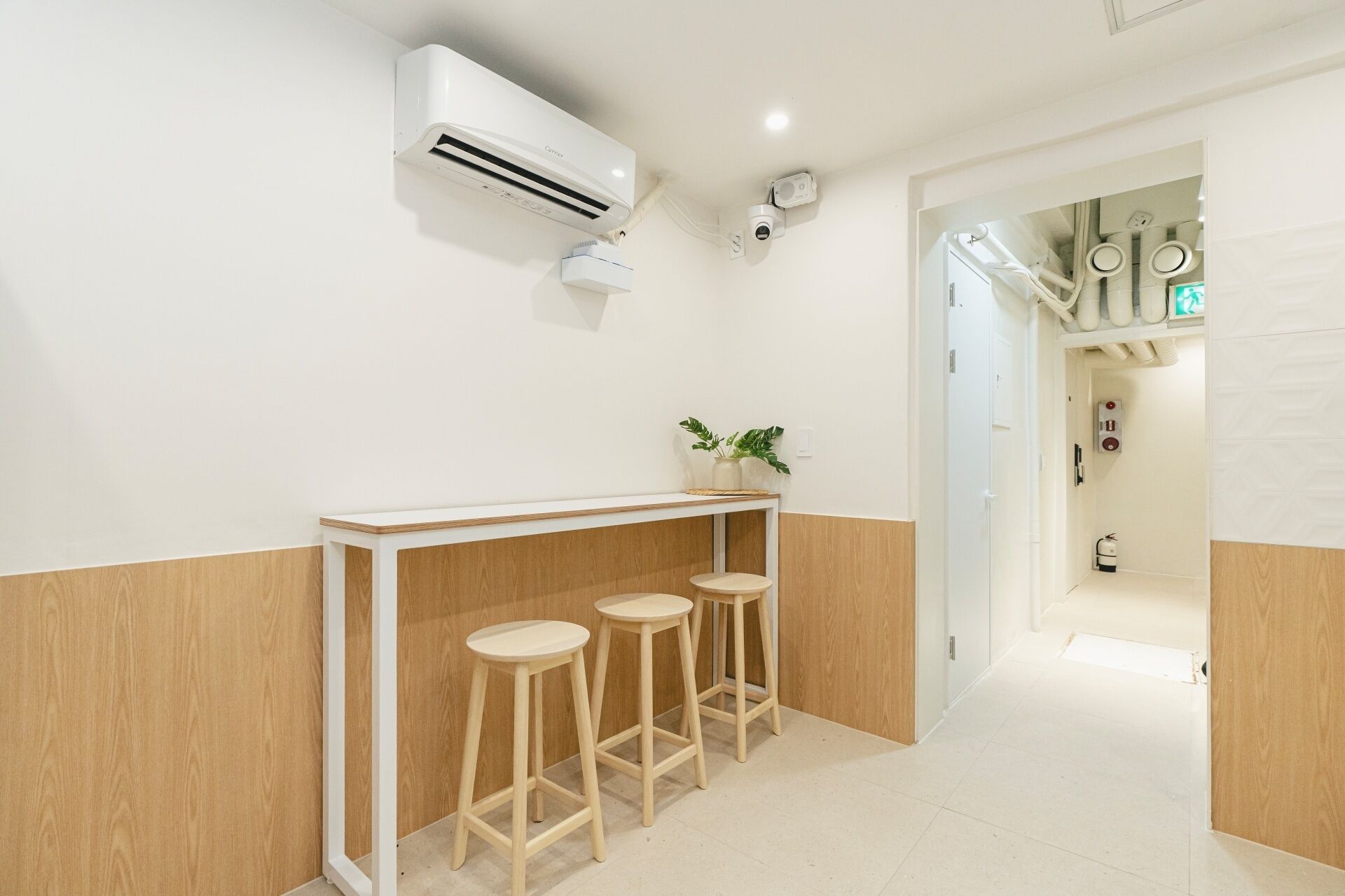 Un baño limpio y moderno con paneles blancos y de madera, un lavabo y dos taburetes.
