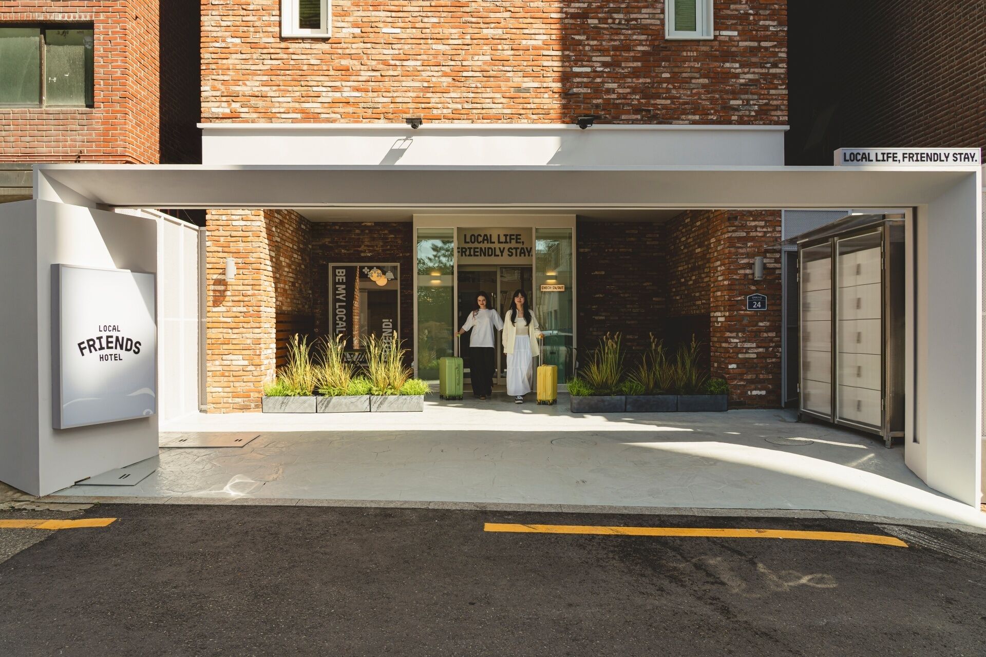 A hotel entrance with a sign reading 'LOCAL FRIENDS HOTEL' and 'LOCAL LIFE, FRIENDLY STAY.'