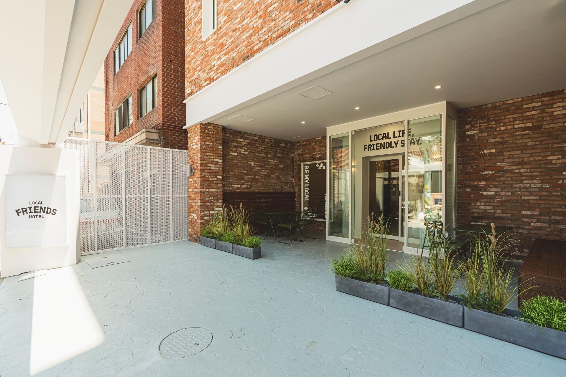 A hotel entrance with a brick facade, a glass door, and outdoor seating with plants.