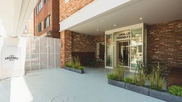 A hotel entrance with a brick facade, a glass door, and outdoor seating with plants.
