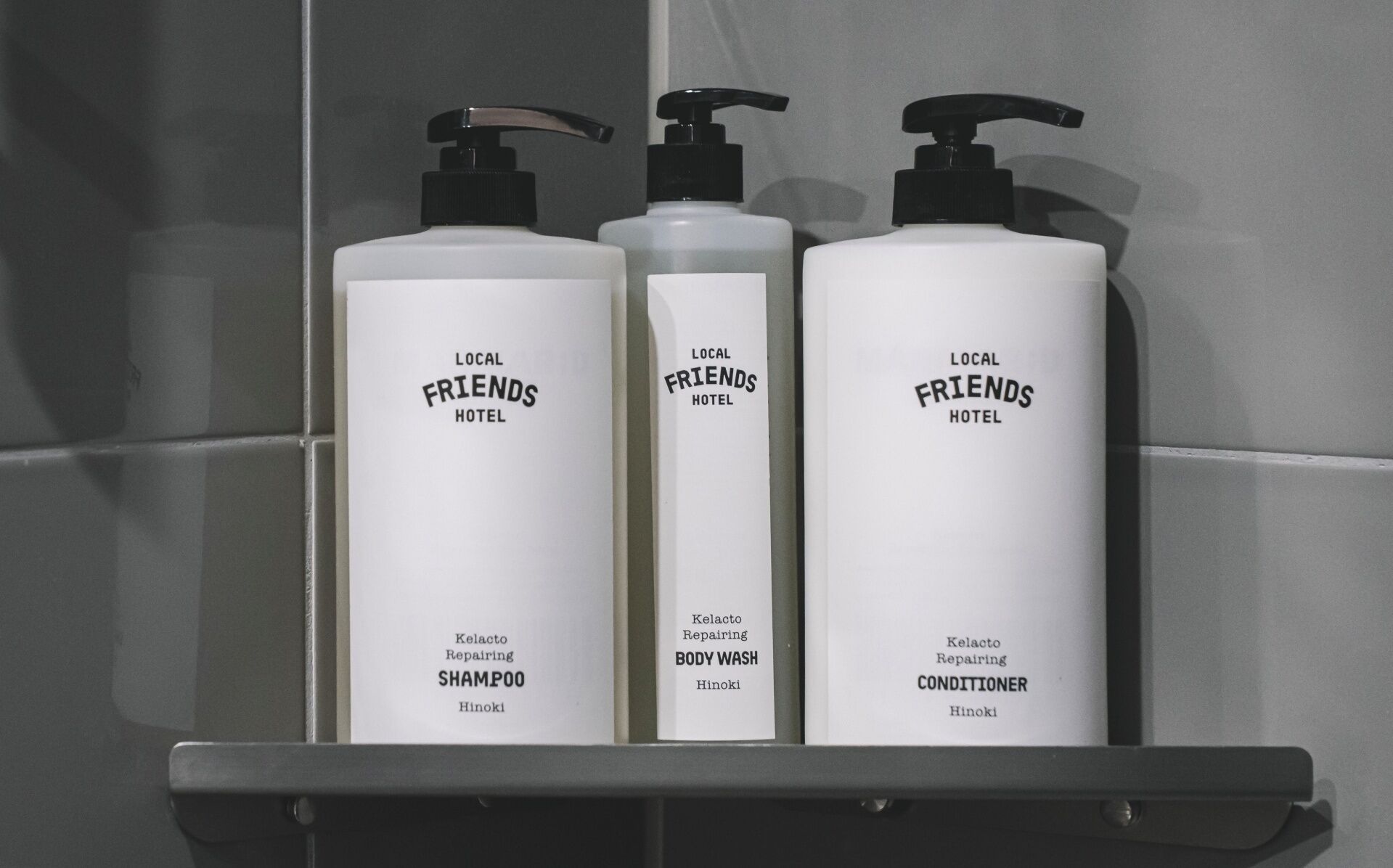 Three bottles of hotel toiletries on a shelf.