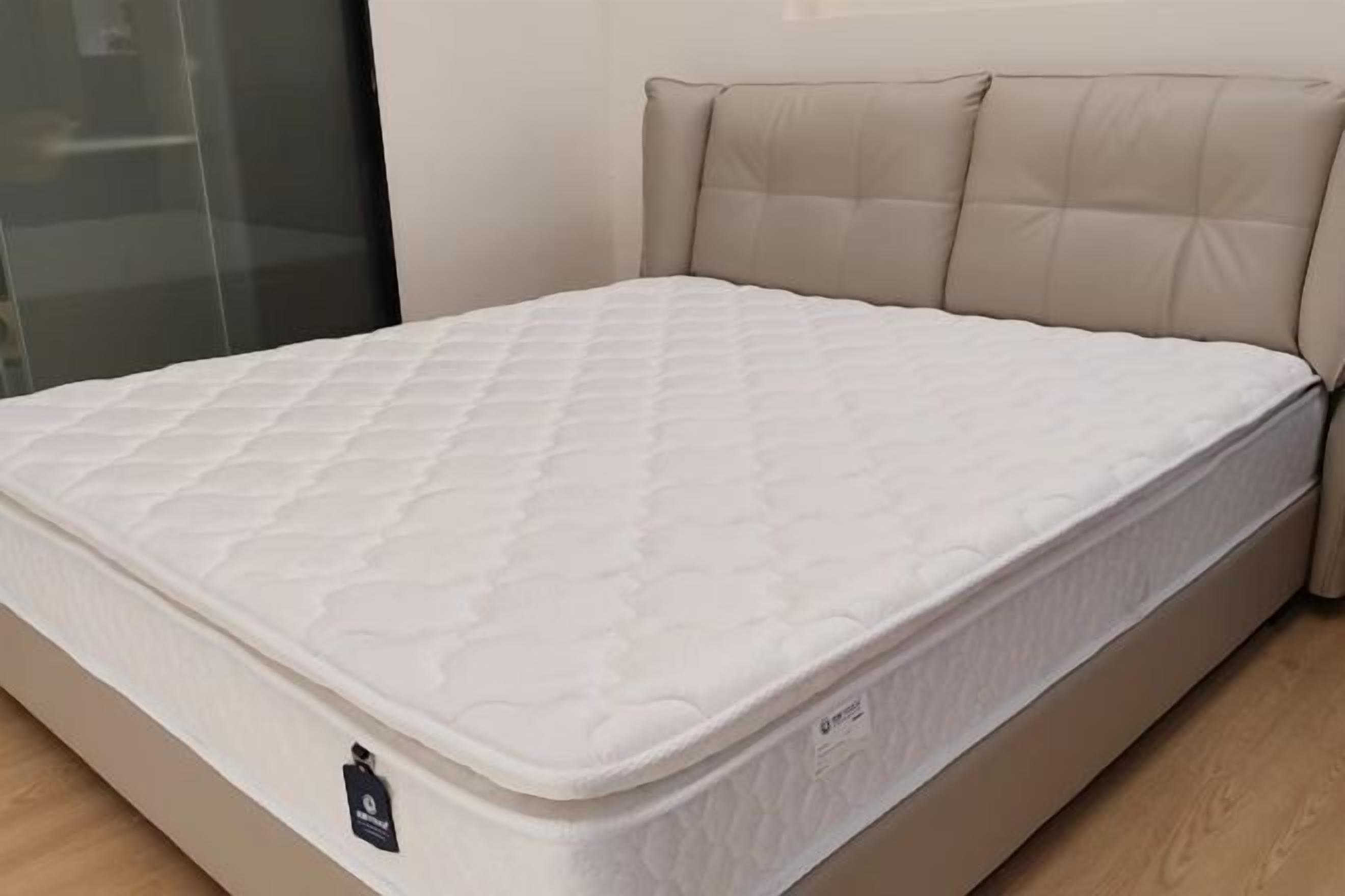 A bed with a quilted mattress and a headboard with tufted panels.