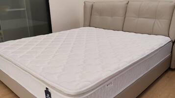 A bed with a quilted mattress and a headboard with tufted panels.