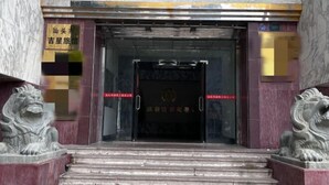 A building entrance with a marble facade, two lion statues, and a signboard. - Jixing Hostel (Shantou)