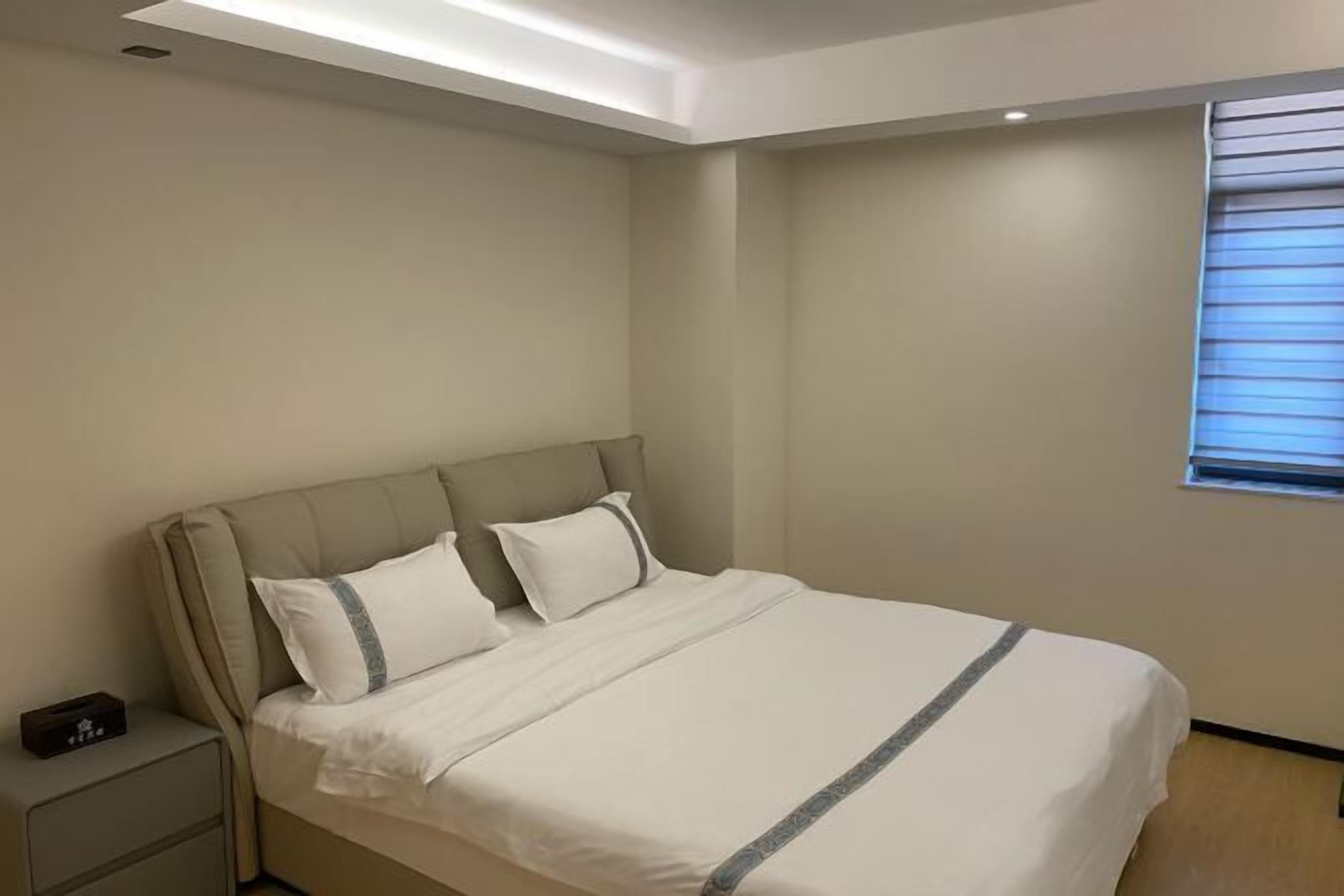 Une chambre à coucher avec un lit, une table de chevet et une fenêtre avec des stores.