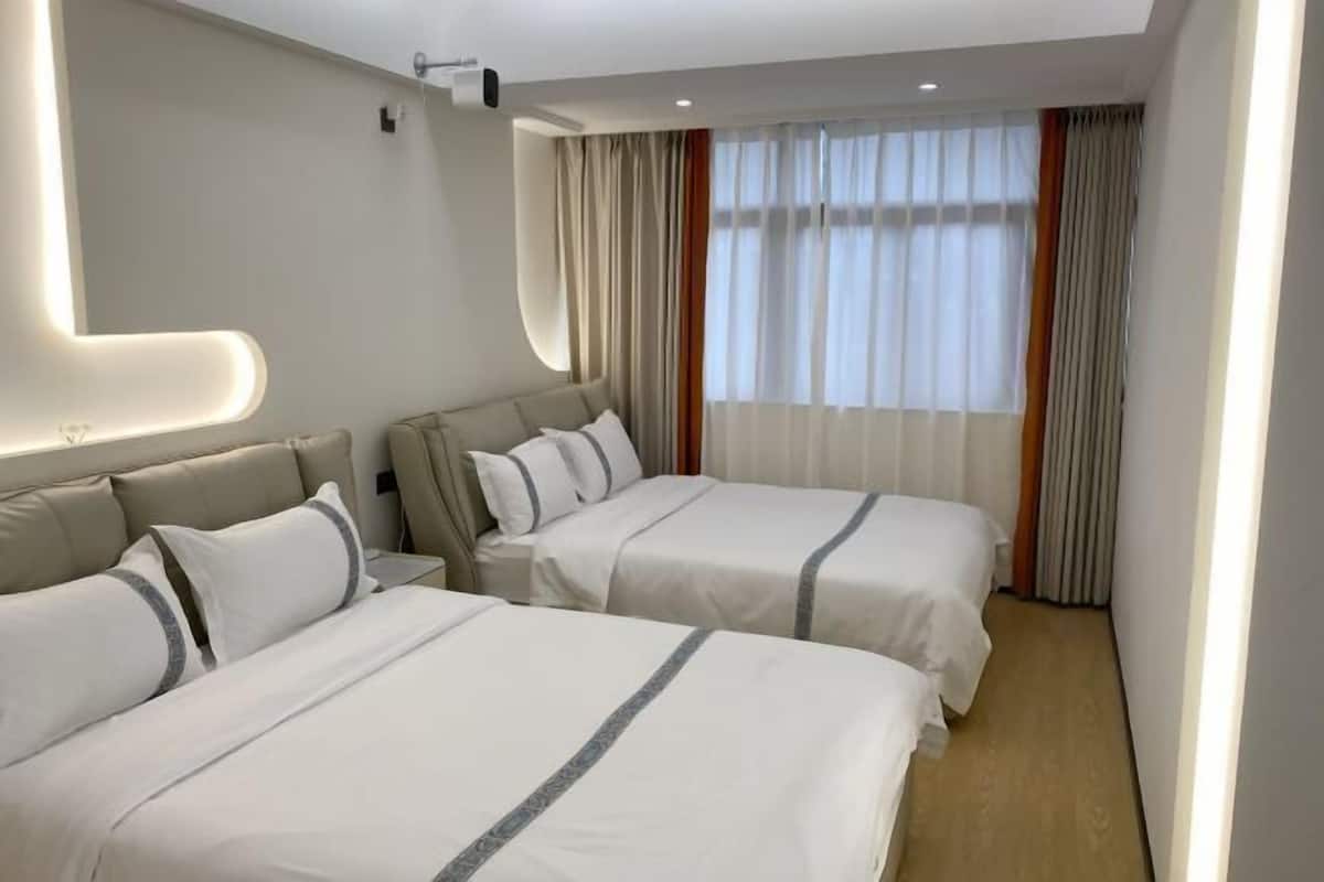 Habitación de hotel con dos camas, un espejo grande y una ventana con cortinas.