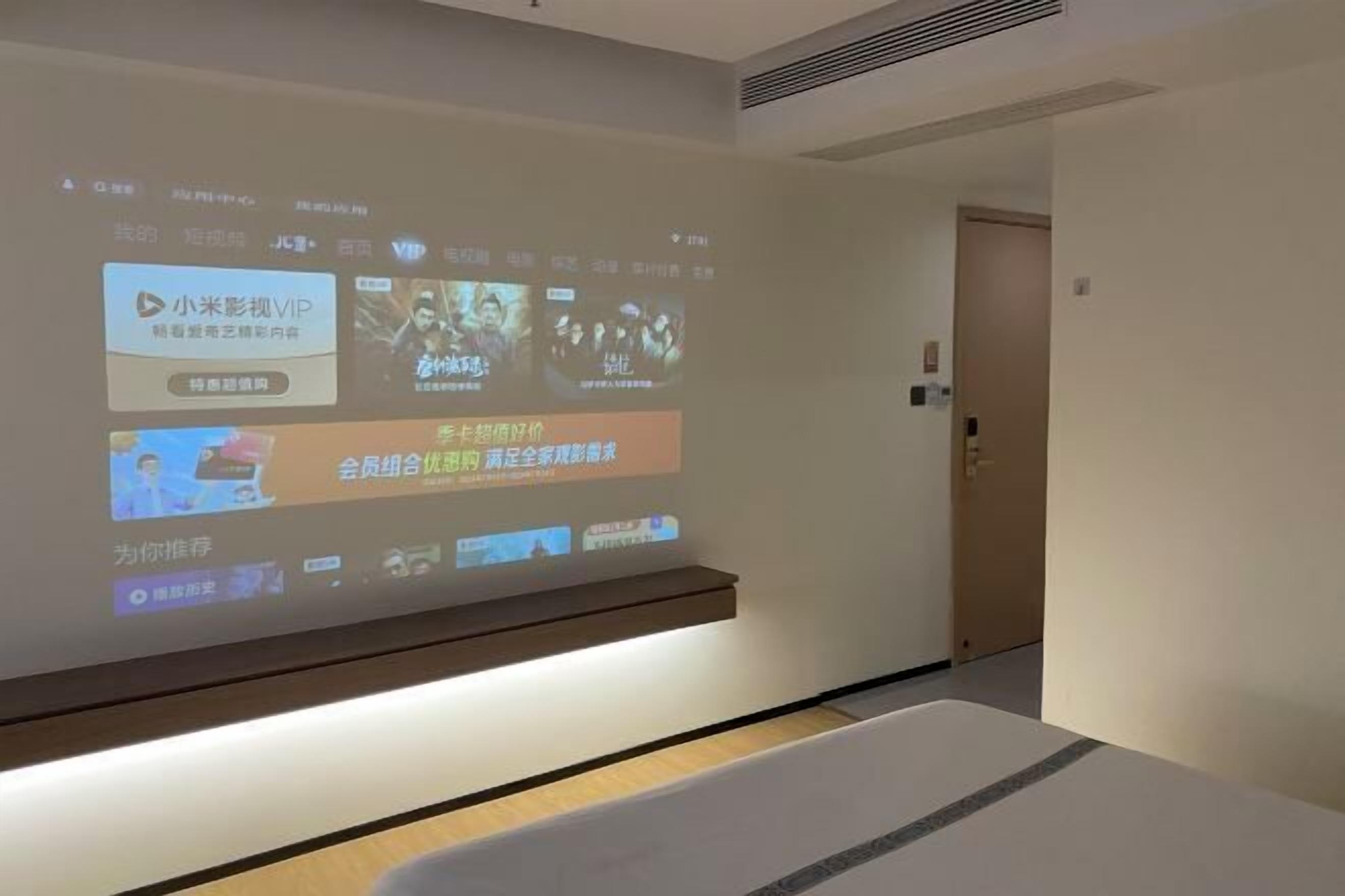 A projection screen displaying various movie titles and a reception area with a reception desk and a door.