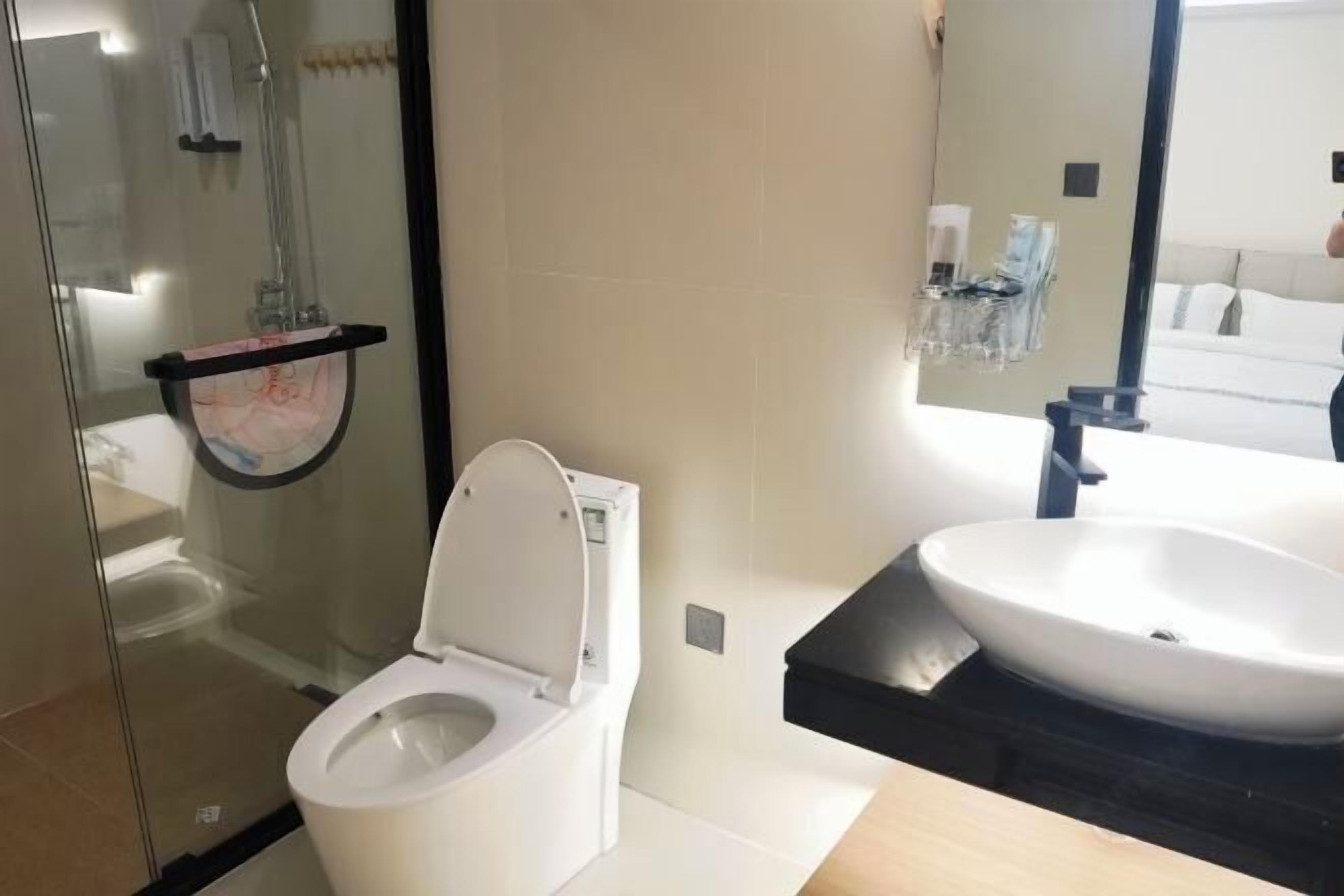 A modern bathroom with a glass-enclosed shower, a white toilet, and a large sink with a black countertop.