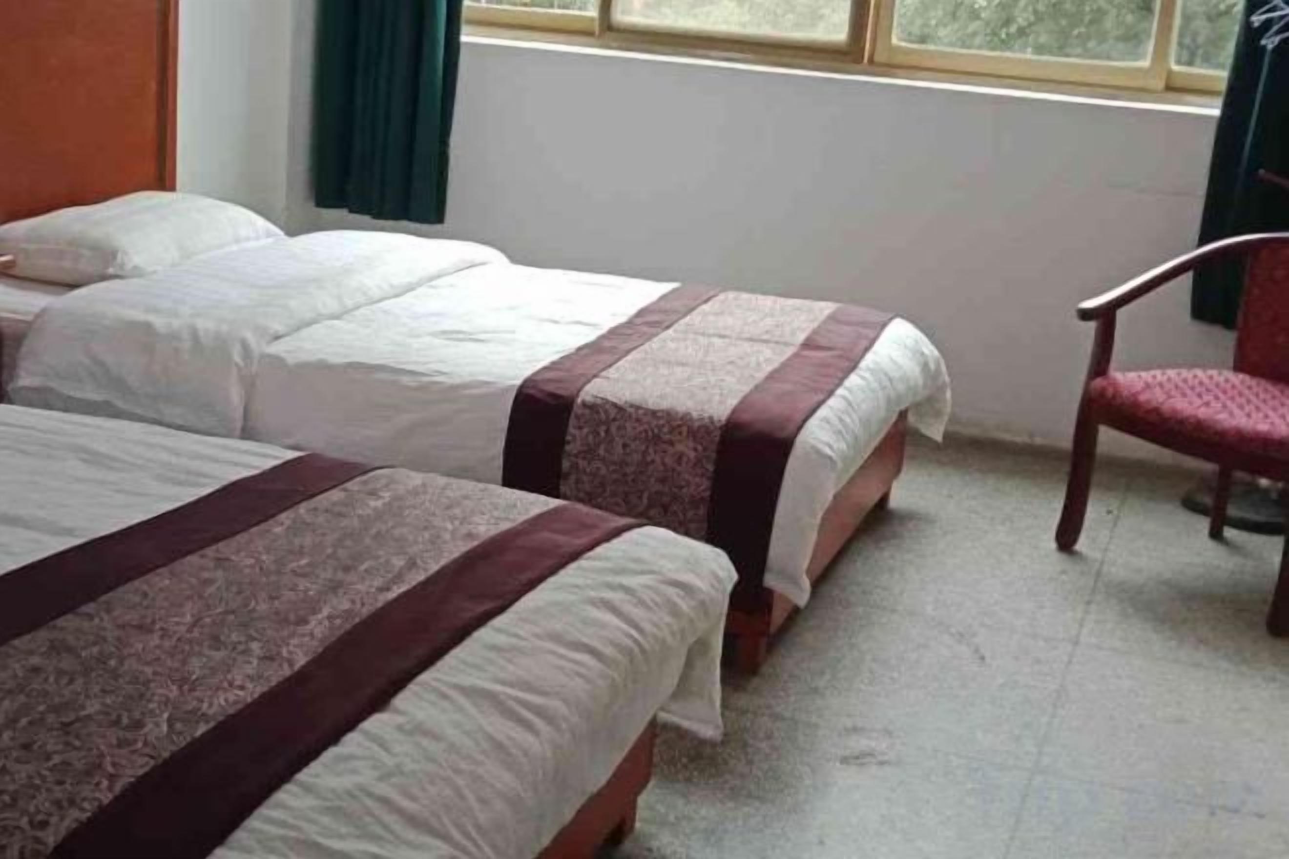 A room with two beds, a chair, and a window.