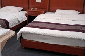 A hotel room with two single beds, wooden headboards, a nightstand with a phone, and a small table with a lamp. - Guxiangqing Hotel (Wuyuan)