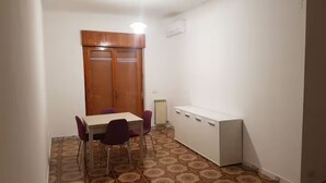 Una stanza piccola con un tavolo, sedie, un termosifone e un armadio in legno.