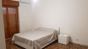 Una camera da letto con un letto, un comodino, un armadio e un pavimento decorato.