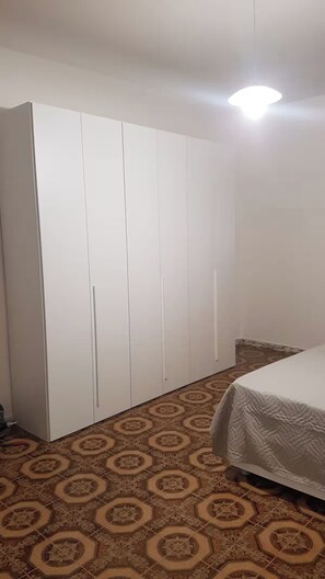 A bedroom with a bed, a wardrobe, and patterned flooring.