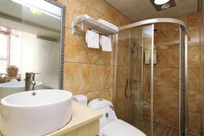 Un bany amb un rentamans blanc, vàter i plat de dutxa amb portes de vidre.
