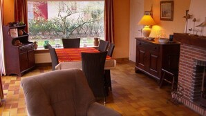 Un salon chaleureux avec une cheminée, une table à manger et un fauteuil confortable.