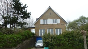 Une maison à deux étages avec une façade en briques, des volets blancs et une porte de garage bleue.