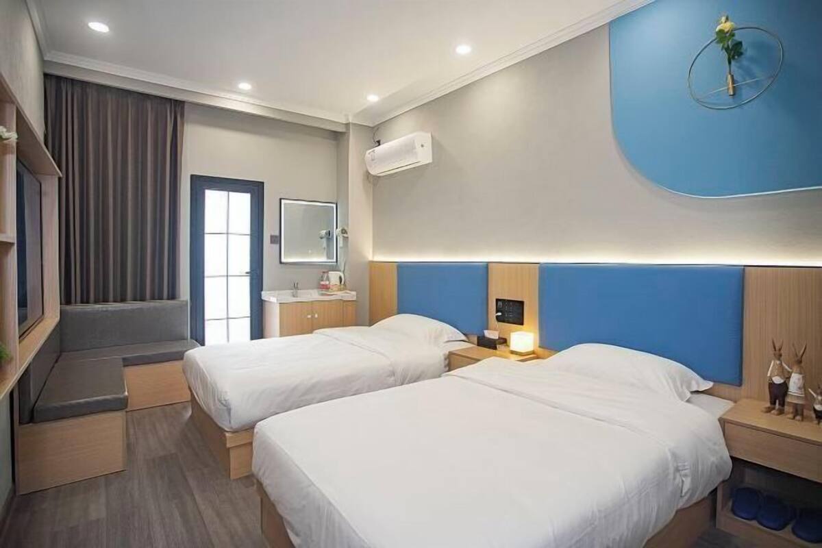 Quarto de hotel com duas camas, banheiro, espelho e escada.