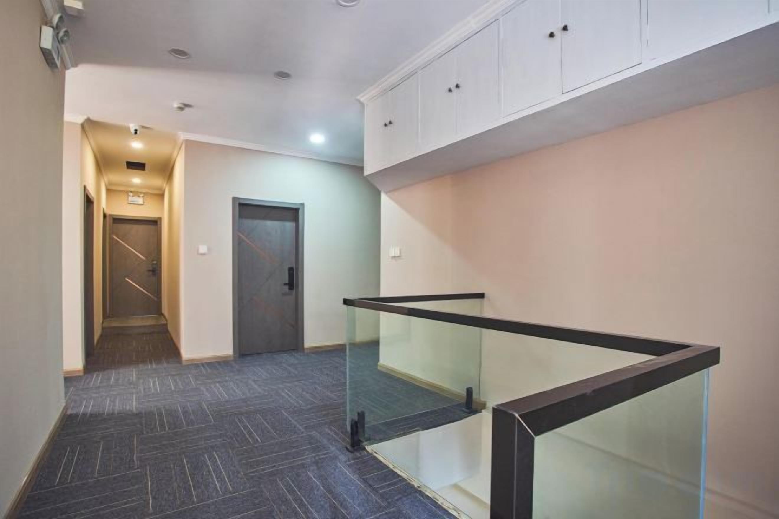 A hallway with a glass railing, a door, and a staircase leading to an upper level.