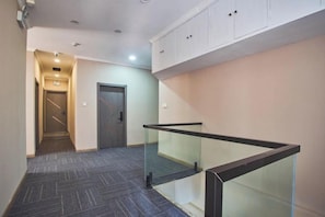 A hallway with a glass railing, a door, and a staircase leading to an upper level. - Lian Hotel (Wuhu)