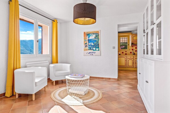 Une pièce lumineuse avec un canapé blanc, une petite table ronde et un tableau accroché au mur.