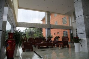 A spacious lobby with marble flooring, multiple seating areas, and a large window overlooking a building. - Junlong Holiday Hotel (Dafang)