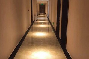 A long, narrow hallway with a reflective floor and doors on both sides. - Junlong Holiday Hotel (Dafang)