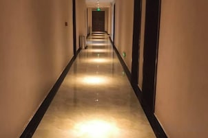 Un pasillo largo y estrecho con piso reflectante y puertas a ambos lados.