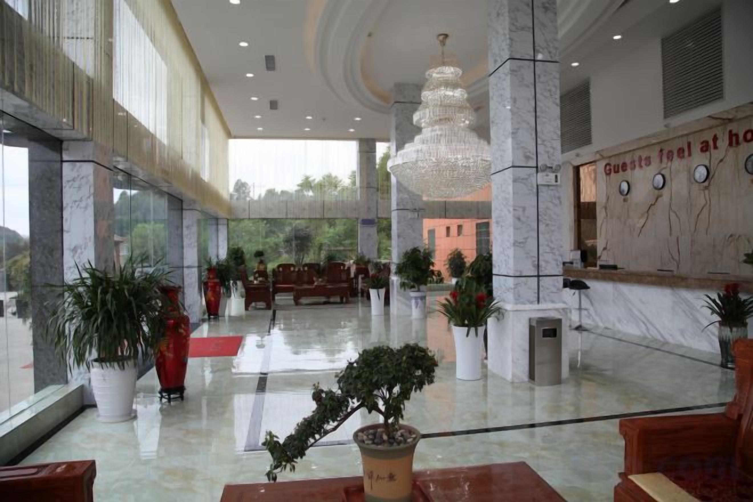 A hotel lobby with marble flooring, a reception desk, and a chandelier.