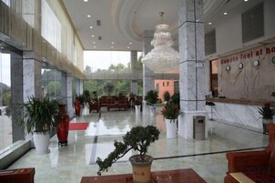 Un hall de hotel con piso de mármol, un mostrador de recepción y un candelabro.